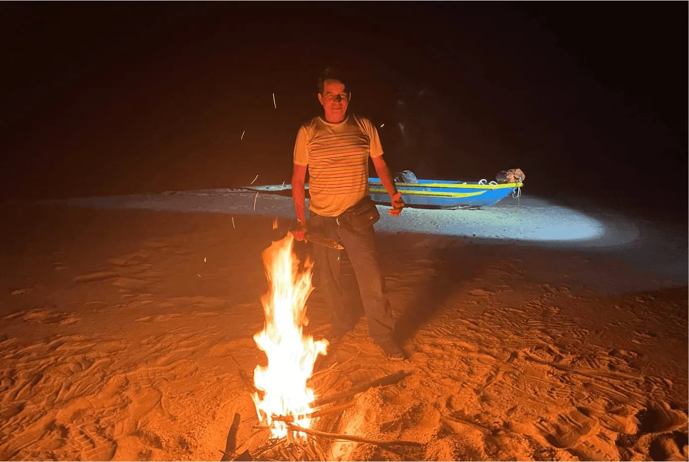 Campfire glowing at a jungle campsite in the Amazon at night