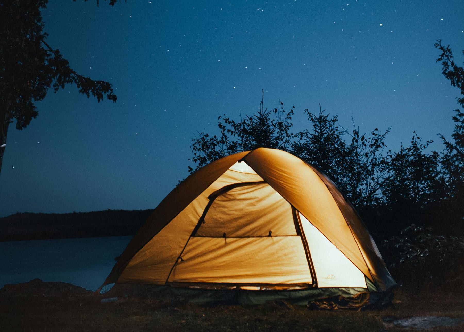 Glowing tent under a starry night sky on an Amazon riverbank