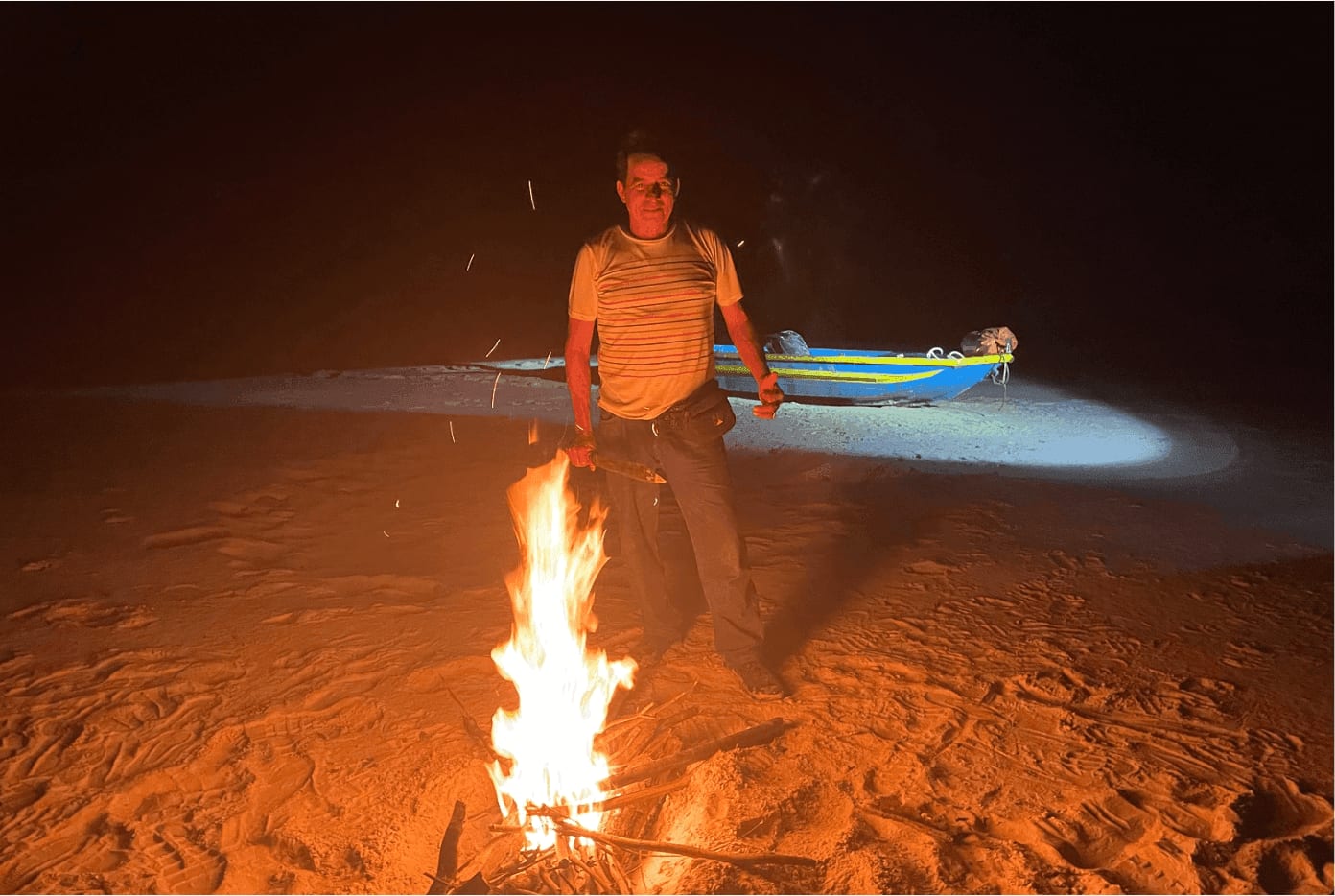 Campfire glowing at a jungle campsite in the Amazon at night