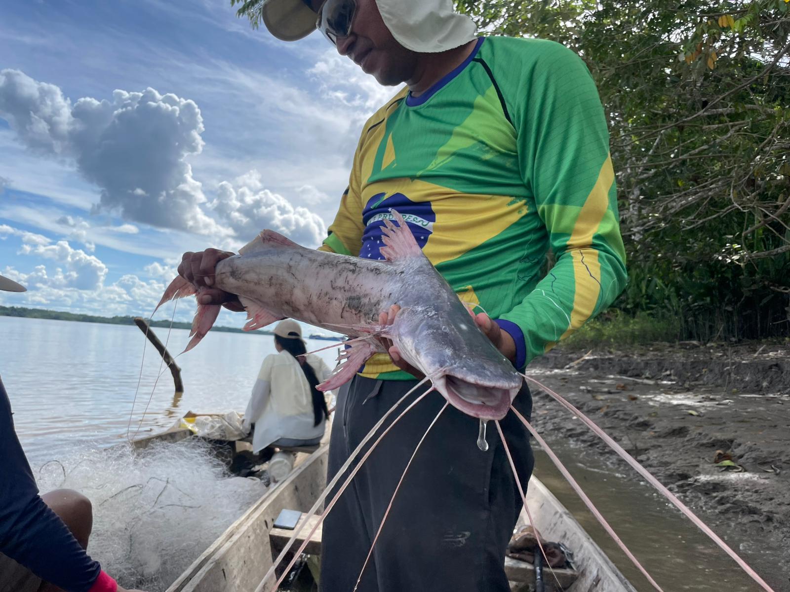 Angler holding a large Amazon catfish on the riverbank near Iquitos
